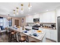 Bright kitchen with granite countertops, an island with seating, and modern appliances at 402 W Clay St, Mebane, NC 27302