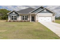 Two-story house with a beige exterior, gray roof, and white garage door at 572 Glenkirk Pl, Garner, NC 27529