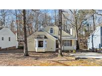 Cute yellow house with wood siding, a white porch, and mature trees surrounding the property at 1322 Cedar Branch Ct, Wake Forest, NC 27587