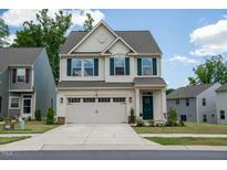 Two-story house with beige vinyl siding, green accents, and a two-car garage at 1604 Ripley Woods St, Wake Forest, NC 27587