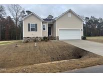 Beige house with a two-car garage and stone accents at 507 Barnes Landing Dr, Four Oaks, NC 27524