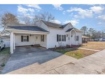Charming white house with a covered carport and well-maintained lawn at 102 S College Ave, Kenly, NC 27542