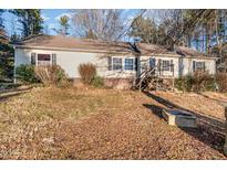 View of a single Gathering home featuring neutral siding, brick foundation, and an overgrown front yard at 1109 Mays Chapel Rd, Bear Creek, NC 27207