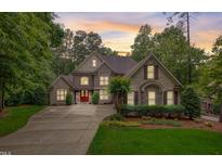 Stately stone home with manicured landscaping, a red front door, and abundant natural light at 1300 Caistor Ln, Raleigh, NC 27614