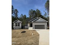Charming single-story home with gray siding, stone accents, an attached garage, and a well-manicured lawn at 65 Watermelon Dr, Franklinton, NC 27525