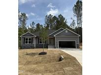 Attractive single-story home with gray siding, stone accents, and an attached two-car garage on a sunny lot at 65 Watermelon Dr, Franklinton, NC 27525