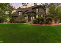 Brick house with stone accents, a large yard, and a three-car garage at 6729 Greywalls Ln, Raleigh, NC 27614