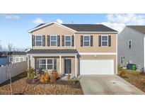 Two-story house with tan siding, white garage door, and landscaping at 105 Kcf Dr, Elon, NC 27244