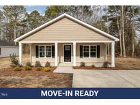Charming single-story home featuring a covered porch, symmetrical windows with black shutters and landscaped front yard at 303 E Pope Ave, Kenly, NC 27542