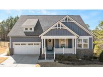 Gray house with white accents and a brick base, featuring a two-car garage and a front porch at 312 Trinity Creek Dr, Holly Springs, NC 27540