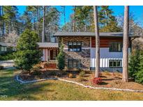 Stunning mid-century modern home with stone and wood siding, landscaped yard, and pergola at 4105 Glen Laurel Dr, Raleigh, NC 27612