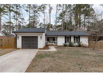 Charming one-story home with a white exterior, dark gray garage door, and landscaped lawn at 1 Cates Ct, Hillsborough, NC 27278