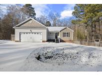 Snow-covered front yard with a two-car garage and neutral siding at 520 Santa Gertrudis Dr, Clayton, NC 27520