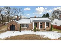 Brick ranch house with covered porch, landscaping, and a detached garage at 927 Bellvue St, Burlington, NC 27217