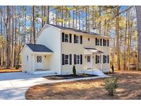 Charming two-story home with a light yellow exterior, black shutters, and well-manicured landscaping at 1006 Sedwick W Rd, Durham, NC 27713