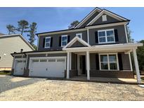 Charming two-story home featuring a three-car garage, gray siding, black shutters, and brick accents at 1109 Opal Ln # 71, Durham, NC 27705