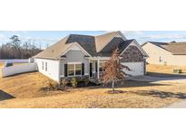 Charming single-Gathering home features stone accents, neutral siding, attached garage, and manicured landscaping at 256 Barbour Farm Ln, Four Oaks, NC 27524