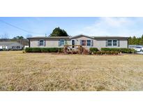 Charming single-story home featuring a cozy front deck, manicured hedges, and a well-maintained lawn at 7945 Nc 42, Holly Springs, NC 27540