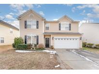 Two-story house with beige siding, black windows, and a white garage door at 112 Smith Rock Dr, Holly Springs, NC 27540