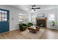 Bright living room with a cozy fireplace, modern ceiling fan and two comfortable green armchairs at 1606 James St, Durham, NC 27707