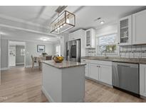 Well-lit kitchen features an island, stainless steel appliances, white cabinets, granite countertops, and an adjacent dining area at 5088 Christian Light Rd, Fuquay Varina, NC 27526