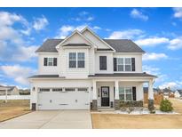 Charming two-story home with white siding, black shutters, covered porch, and a two car garage at 8 Looping Horse Cir, Angier, NC 27501