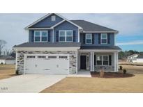 Two-story house with gray siding, stone accents, and a three-car garage at 107 Northwood Dr, Fuquay Varina, NC 27526