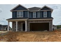 Two-story home featuring gray stone and siding, attached two-car garage, and a covered front porch with white pillars at 128 High Hampton Way, Fuquay Varina, NC 27526