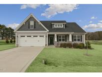 Gray two-story house with white garage door and landscaped lawn at 129 Colby Farm Dr, Kenly, NC 27542