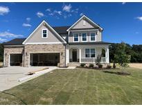 Beautiful two-story home featuring stone accents, a front porch, attached two-car garage, and a well-maintained lawn at 71 Priming Way, Angier, NC 27501