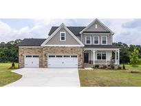 Charming two-story home features a stone facade, inviting front porch, three-car garage, and well-manicured lawn at 71 Priming Way, Angier, NC 27501