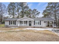 Gray exterior house with covered porch, landscaping, and driveway at 7516 Fox Rd, Raleigh, NC 27616