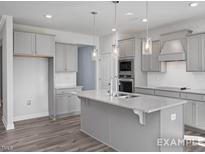 Modern kitchen with island, stainless steel appliances, and gray cabinets at 71 Priming Way, Angier, NC 27501