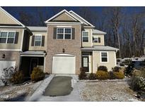 Two-story townhome with brick and siding exterior, attached garage, and snowy landscaping at 133 Walking Path Pl, Hillsborough, NC 27278