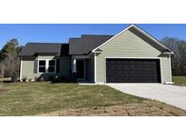 Newly constructed home with green vinyl siding, a black garage door, and well-manicured lawn at 164 Phil Jack Rd, Dunn, NC 28334