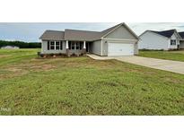 Charming single-story home with a two-car garage, tidy landscaping and neutral gray siding at 185 N Movado Trl, Kenly, NC 27542