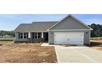 Charming single-story home featuring gray siding, a two-car garage, and a well-lit entrance at 185 N Movado Trl, Kenly, NC 27542