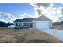 Charming single-story home with gray siding, a two-car garage, and a well-manicured front yard at 185 N Movado Trl, Kenly, NC 27542