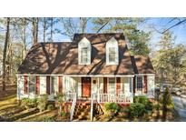 Charming two-story home with red shutters and a welcoming front porch, surrounded by lush landscaping at 1909 Pearces Rd, Zebulon, NC 27597
