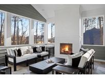 A cozy sunroom with a fireplace, comfortable seating, and large windows offering a view of the outdoors at 2721 Sanctuary Woods Ln, Raleigh, NC 27606