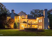 A well lit backyard with a spiral staircase leading to the deck and beautiful manicured green lawn at 11201 Jonas Ridge Ln, Raleigh, NC 27613