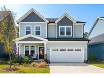 Two-story light green house with gray accents, white garage door, and landscaped front yard at 166 Retreat Dr, Fuquay Varina, NC 27526