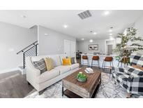 Bright living room featuring a modern sofa, stylish decor, and seamless flow to the kitchen area at 313 E Fourth St, Wendell, NC 27591