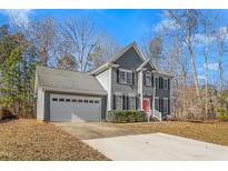 Two-story gray house with a red door, white garage door, and landscaping at 300 Ashwick Dr, Efland, NC 27243