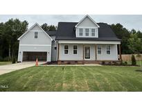 Charming two-story home boasts a welcoming front porch, attached garage, and a lush green lawn at 404 Brodie Rose Landing Way, Smithfield, NC 27577