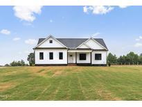 Beautifully landscaped modern farmhouse-style home with a lush, green front yard on a sunny day at 541 Delma Grimes Rd, Coats, NC 27521