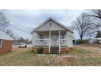 White house with front porch and small yard at 1411 Piedmont Way, Burlington, NC 27217