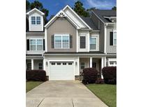 Two-story townhome with gray siding, white garage door, and landscaping at 166 Gulley Glen Dr, Garner, NC 27529
