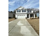 Charming two-story home features a spacious driveway, attached two-car garage, and inviting covered front porch at 237 Hopewell Branch Ct, Smithfield, NC 27577