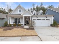 Gray two-story house with white trim, two-car garage, and landscaped front yard at 2515 Impulsion Dr, New Hill, NC 27562